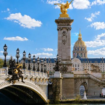 The Pont Alexandre III is a majestic Beaux-Arts bridge adorned with ornate golden statues and lamp posts that connect the Champs-Élysées to the Invalides across the Seine.