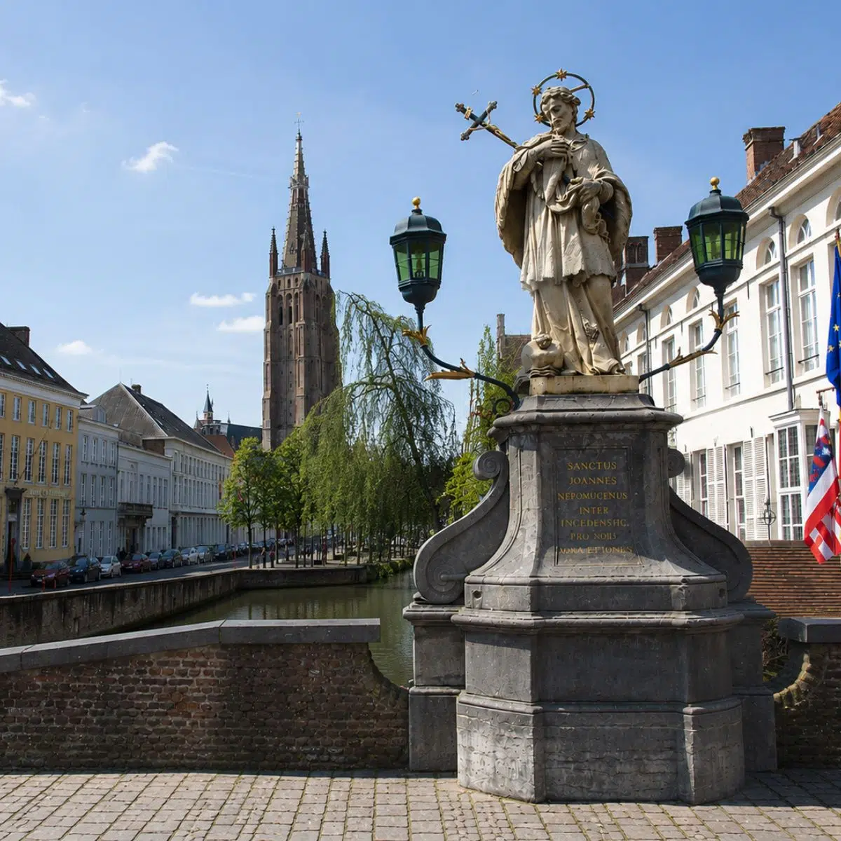 Chasse au trésor et visite guidée de Bruges 5 Nommé en l'honneur de saint Jean Népomucène, ce pont de pierre pittoresque offre une vue digne d'une carte postale sur les canaux historiques de Bruges, où les saules pleureurs effleurent délicatement l'eau, lisse comme un miroir.