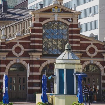 De Oude Markthal is een majestueus historisch monument waar een grote bakstenen gevel en elegante houten kraampjes een monumentaal middelpunt vormen voor de culinaire tradities van Helsinki.