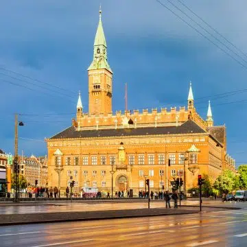 A Câmara Municipal de Copenhaga é um grande edifício romântico nacional inspirado na arquitetura de Siena, com uma rica fachada de tijolo vermelho e uma icónica torre do relógio de 105 metros. Funciona como o coração administrativo da cidade e alberga o Relógio Mundial de Jens Olsen, uma obra-prima de precisão mecânica que apresenta posições astronómicas com uma exatidão incrível.