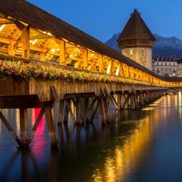 The Kapellbrücke is the world's oldest covered wooden footbridge and serves as the iconic symbol of Lucerne, stretching diagonally across the Reuss River. This 14th-century landmark is famous for its interior triangular paintings depicting local history and its adjacent octagonal Water Tower, which once served as a treasury and a prison.