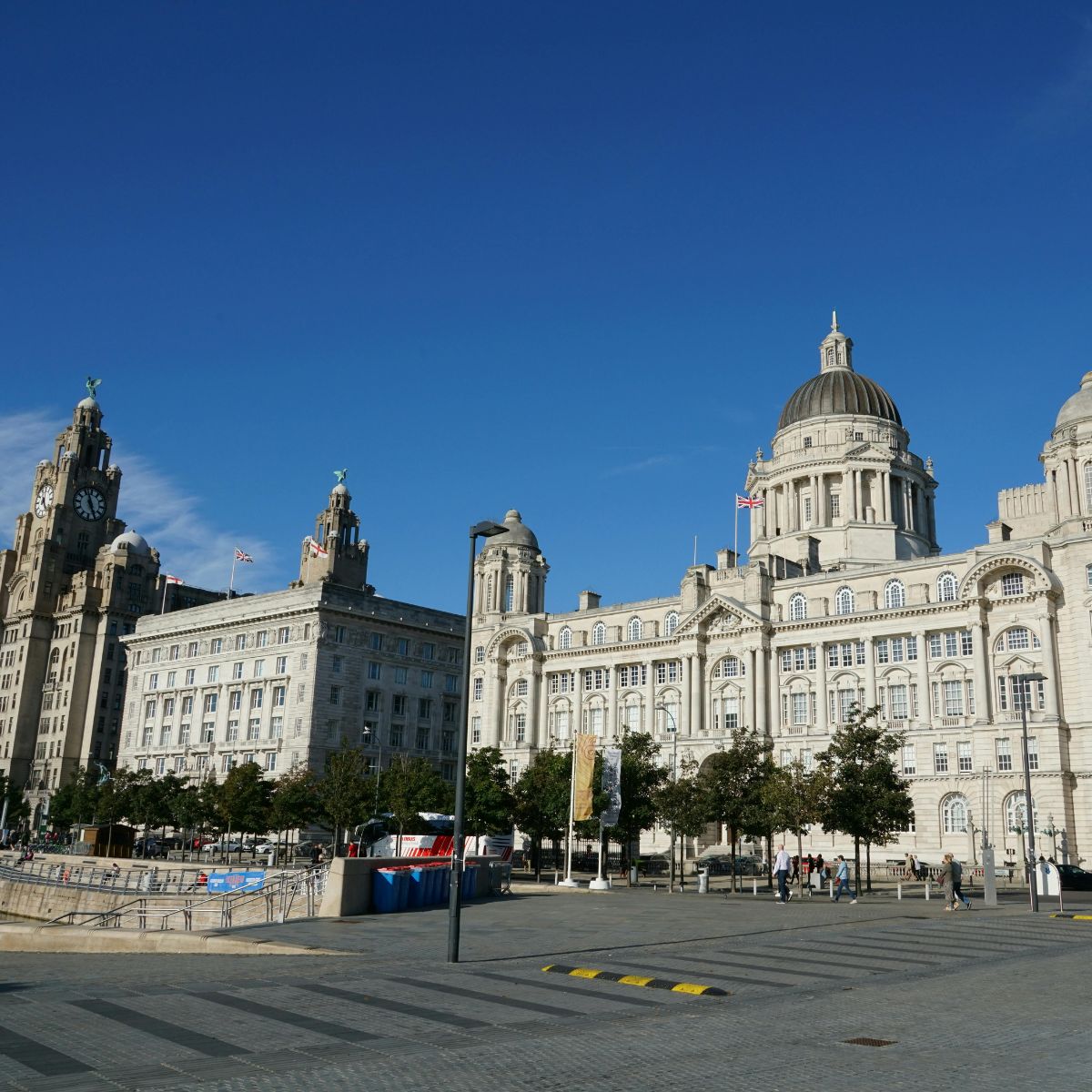 Schnitzeljagd und selbstgeführte Tour durch Liverpool 4 Die drei Grazien sind ein majestätisches Ensemble edwardianischer Wahrzeichen, in dem das große Royal Liver Building, das Cunard Building und das Port of Liverpool Building eine monumentale Skyline am Wasser bilden, die das maritime Erbe der Stadt prägt.