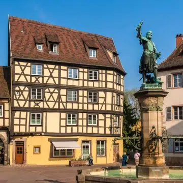 La Place de l'Ancienne Douane è una pittoresca piazza medievale di Colmar, ancorata dallo storico Koïfhus e circondata da colorati edifici a graticcio. Al centro si trova la Fontana di Schwendi, con una statua in bronzo di Bartholdi che celebra la leggenda locale della storia del vino alsaziano.