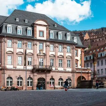 Heidelberger Marktplatz è il cuore pulsante del centro storico di Heidelberg, dove lo splendido municipio barocco e la storica chiesa dello Spirito Santo sono incorniciati da vivaci caffè all'aperto e dalla vista del maestoso castello.