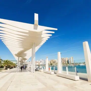 Het Palmeral de las Sorpresas is een stijlvolle promenade aan zee die wordt gekenmerkt door de hoge witte golvende pergola en weelderige palmentuinen die de stedelijke energie van de stad vermengen met de mediterrane kust.