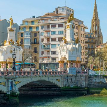La zubia de María Cristina es un majestuoso puente de piedra donde grandes obeliscos coronados por dragones y elegantes lámparas de la Belle Époque cruzan el río Urumea como monumental puerta de entrada a la ciudad.