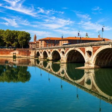 The Pont Neuf is a majestic Renaissance landmark where a grand seven-arched stone bridge and historic asymmetrical openings create a monumental masterpiece spanning the Garonne River in Toulouse.