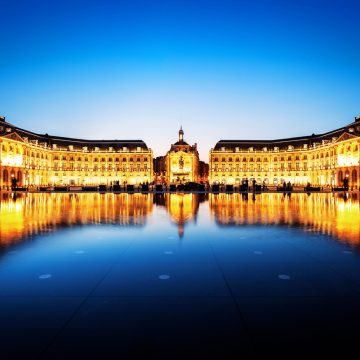 Η Place de la Bourse είναι ένα αριστούργημα της γαλλικής αρχιτεκτονικής του 18ου αιώνα που λάμπει λαμπρά το σούρουπο καθώς αντανακλάται στα λαμπερά νερά του Miroir d'eau.