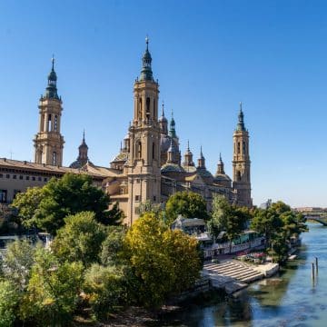 La basilique Notre-Dame-du-Pilar de Saragosse est un magnifique édifice baroque situé au bord de l'Èbre, réputé pour ses imposants dômes, ses tours vertigineuses, son intérieur richement décoré et sa profonde signification religieuse.