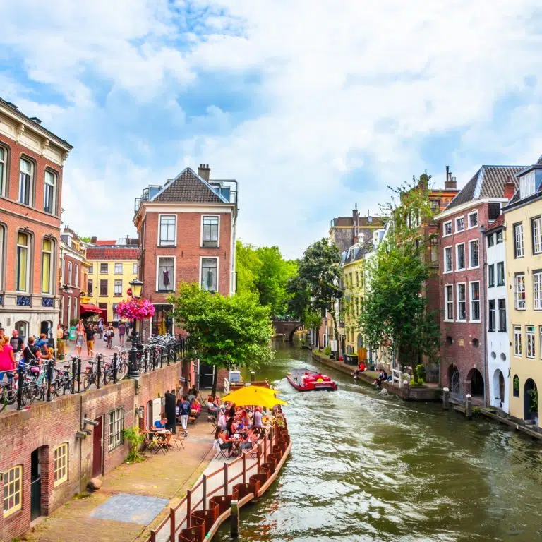 Juego de pistas y visita autoguiada por Utrecht 5 El Oudegracht es el canal más famoso de Utrecht, único por sus muelles y bodegas medievales a dos niveles que ahora albergan vibrantes cafés y boutiques a ras de agua. Esta histórica vía navegable de tres kilómetros sirvió de puerto interior durante siglos, y su trazado curvo sigue un antiguo brazo del Rin, creando un pintoresco corazón para la vida social de la ciudad.