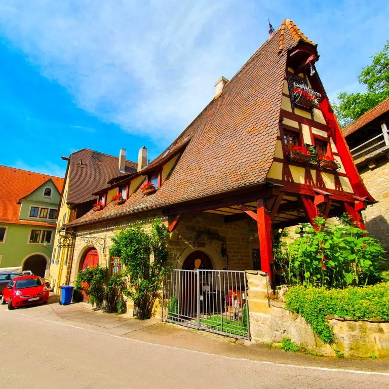 Speurtocht en rondleiding op eigen houtje in Rothenburg 3 De Gerlachschmiede is een opvallend pittoresk vakwerkhuis dat na oorlogsschade werd herbouwd om de iconische puntgevel en het traditionele vakmanschap te laten zien. Dit charmante bouwwerk blijft een van de meest gefotografeerde plekken in de stad en is een bewijs van de zorgvuldige architectonische restauratie van het middeleeuwse erfgoed van Rothenburg.