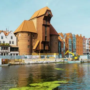 La Gru di Danzica è un'imponente gru portuale medievale e una porta fortificata che rappresenta un potente simbolo della storia commerciale marittima della città. Alimentata da gigantesche ruote di legno, un tempo era la più grande del suo genere in Europa e veniva utilizzata per caricare il carico e per calzare gli alberi delle navi mercantili.