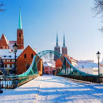 The Tumski Bridge is a charming turquoise-colored steel structure that serves as the romantic gateway between the mainland and the historic Cathedral Island. Known traditionally as the "Bridge of Lovers," it is a focal point for local folklore and is still illuminated by the soft glow of original gas lamps hand-lit every evening.