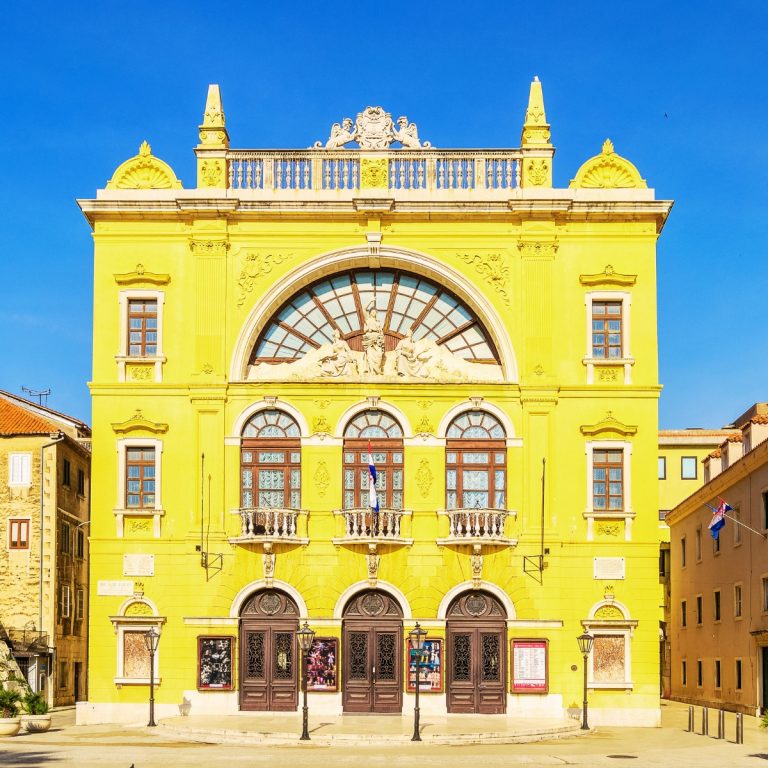 Búsqueda del tesoro dividida y visita autoguiada 6 El Teatro Nacional Croata de Split es un llamativo monumento neorrenacentista conocido por su vibrante fachada amarilla y su rica historia como una de las principales instituciones culturales más antiguas de Dalmacia.
