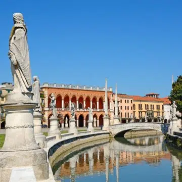 Prato della Valle è una maestosa piazza ellittica, una delle più grandi d'Europa, con un canale fiancheggiato da statue che circonda una lussureggiante isola centrale.