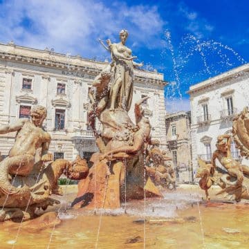 Situada en el centro de la Piazza Archimede, en la isla de Ortigia, la monumental Fuente de Diana (Fontana di Diana) representa el mito de la ninfa Aretusa, a quien la diosa Diana transformó en un manantial de agua dulce para que escapara del dios fluvial Alfeo.