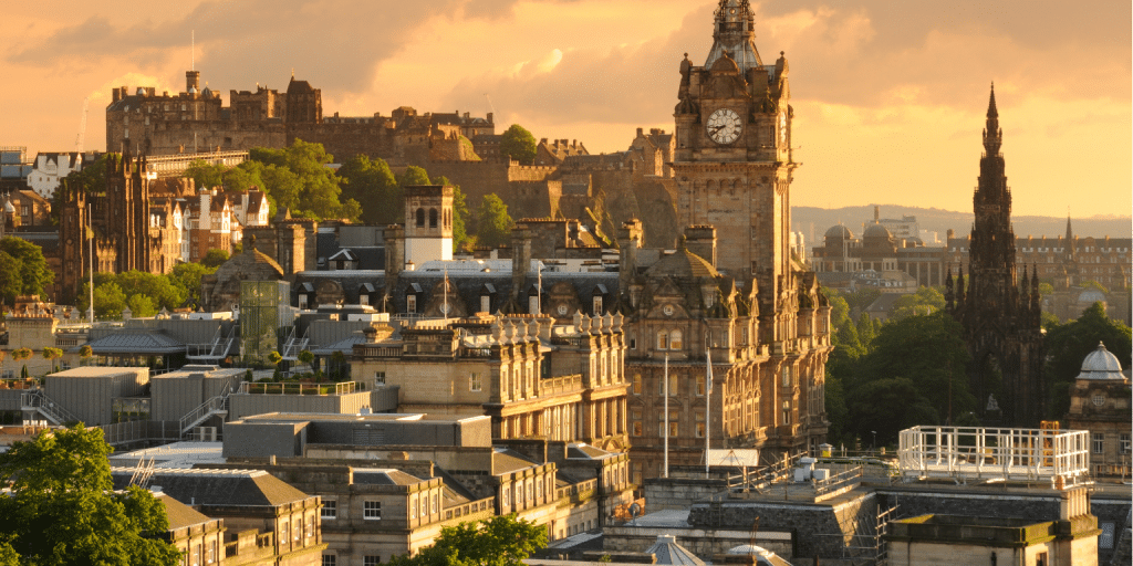 Edimburgo histórico: Guía de las mejores actividades de la ciudad 1 un gran edificio con una torre del reloj y un castillo al fondo
