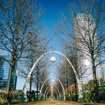 Klyde Warren Park in Dallas is a vibrant green space built above a downtown freeway, with lawns, gardens, fountains, and gathering areas surrounded by the striking skyline of the Dallas Arts District.