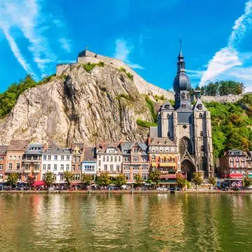 De collegiale Onze-Lieve-Vrouwekerk is een prachtig 13e-eeuws gotisch monument in Dinant, direct herkenbaar aan de unieke peervormige klokkentoren tegen de dramatische achtergrond van een torenhoge kalksteenrots.