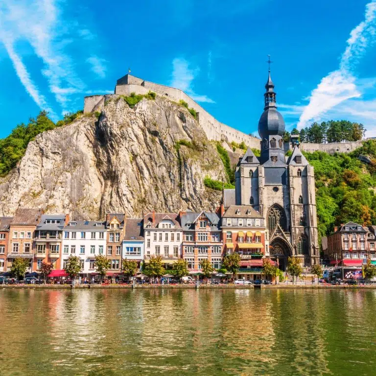Speurtocht en rondleiding op eigen houtje in Dinant 4 De collegiale Onze-Lieve-Vrouwekerk is een prachtig 13e-eeuws gotisch monument in Dinant, direct herkenbaar aan de unieke peervormige klokkentoren tegen de dramatische achtergrond van een torenhoge kalksteenrots.