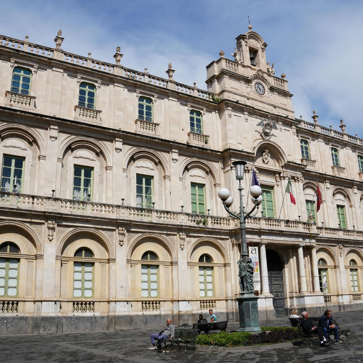 Speurtocht en rondleiding op eigen houtje in Catania 4 Piazza Università is een majestueuze Siciliaanse barokke bezienswaardigheid waar een grote verzameling historische universiteitspaleizen en artistieke bronzen lantaarnpalen een monumentaal architectonisch hart vormen voor het academische leven in Catania.