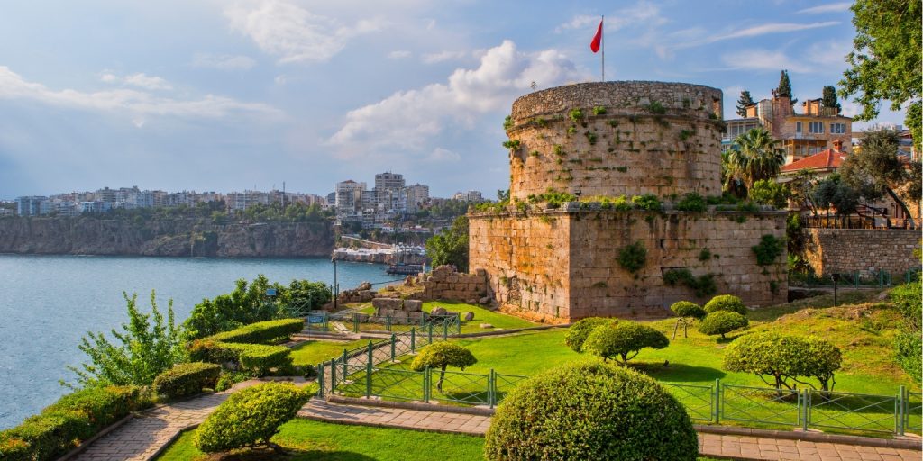Gezinsactiviteit in Antalya 4 een stenen toren met een vlag erop met de Hıdırlık Toren op de achtergrond